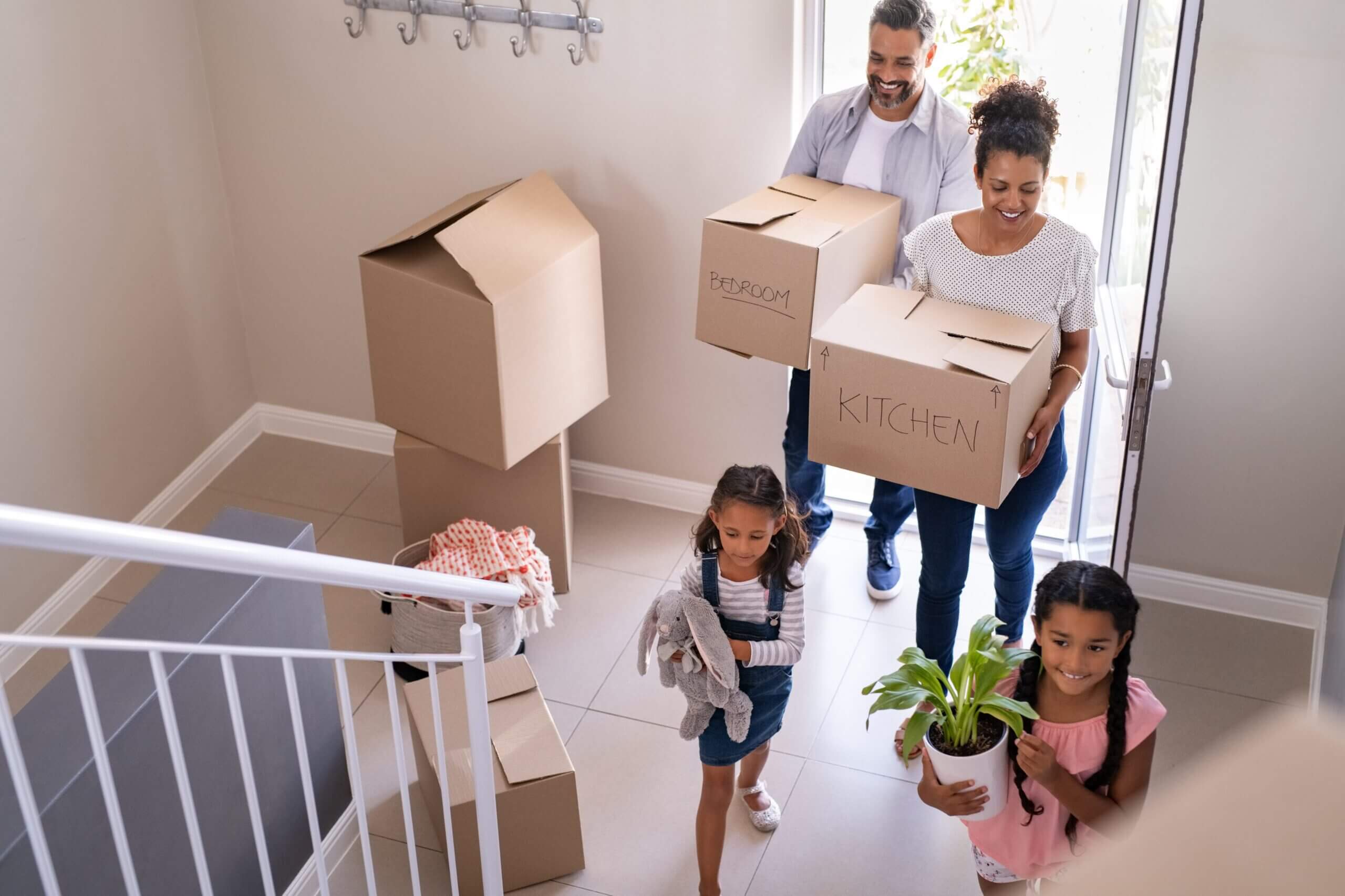 Family carrying boxes into new home.
